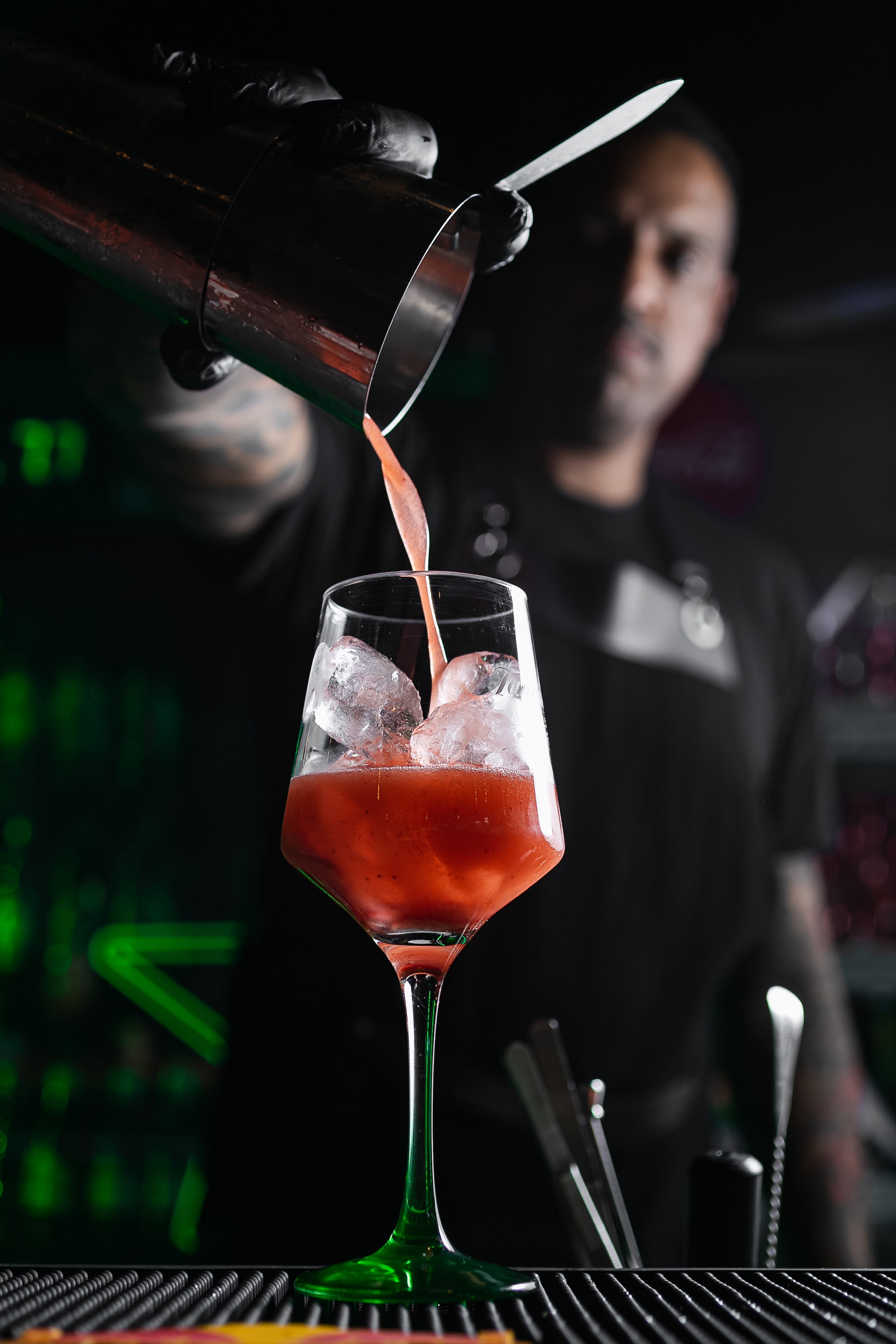 Coquetel vermelho sendo preparado por um profissional de bar
