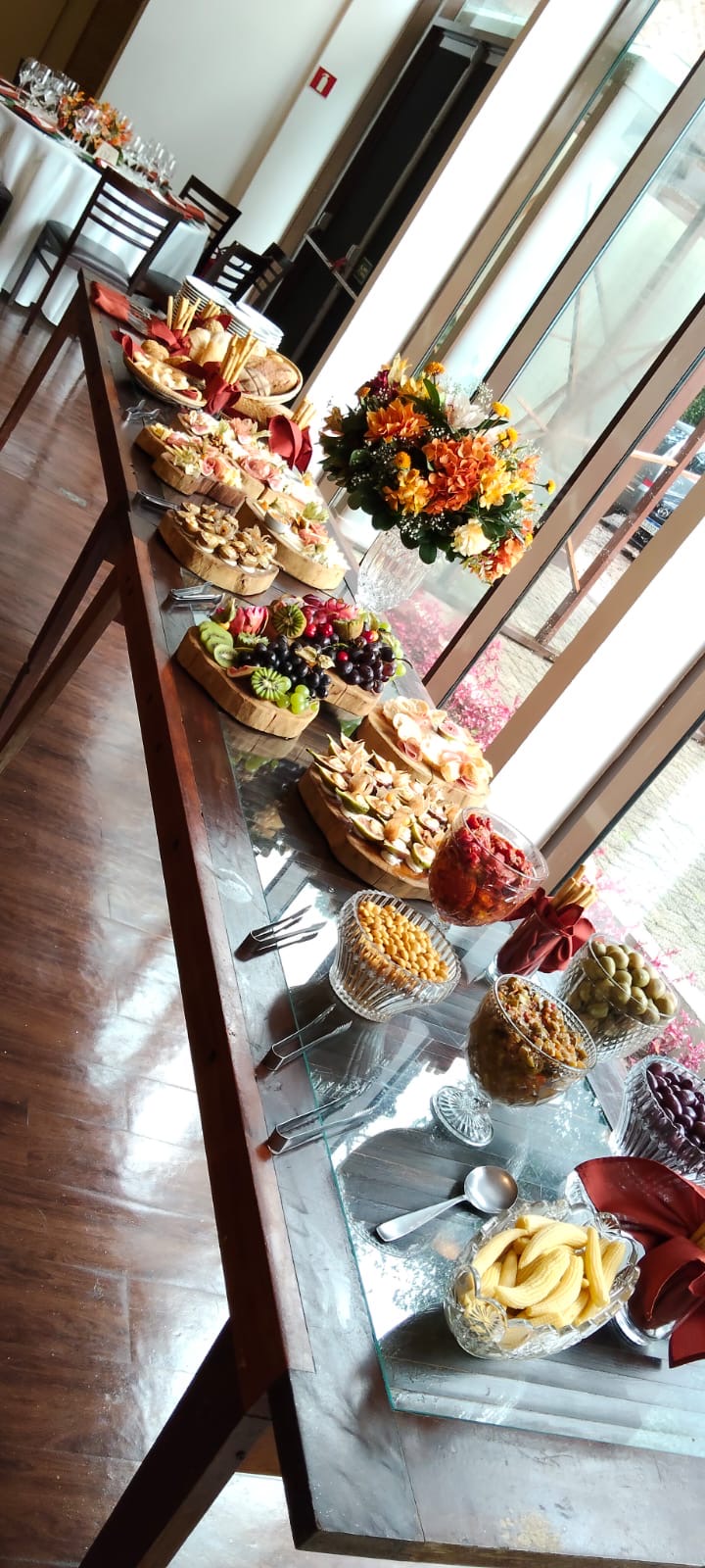 Mesa de evento com petiscos, frutas e flores